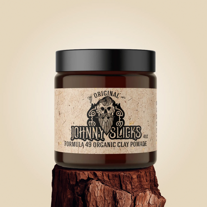 Jar of Johnny Slicks organic clay pomade on a wooden block with a beige background