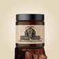 Jar of Johnny Slicks organic clay pomade on a wooden block with a beige background